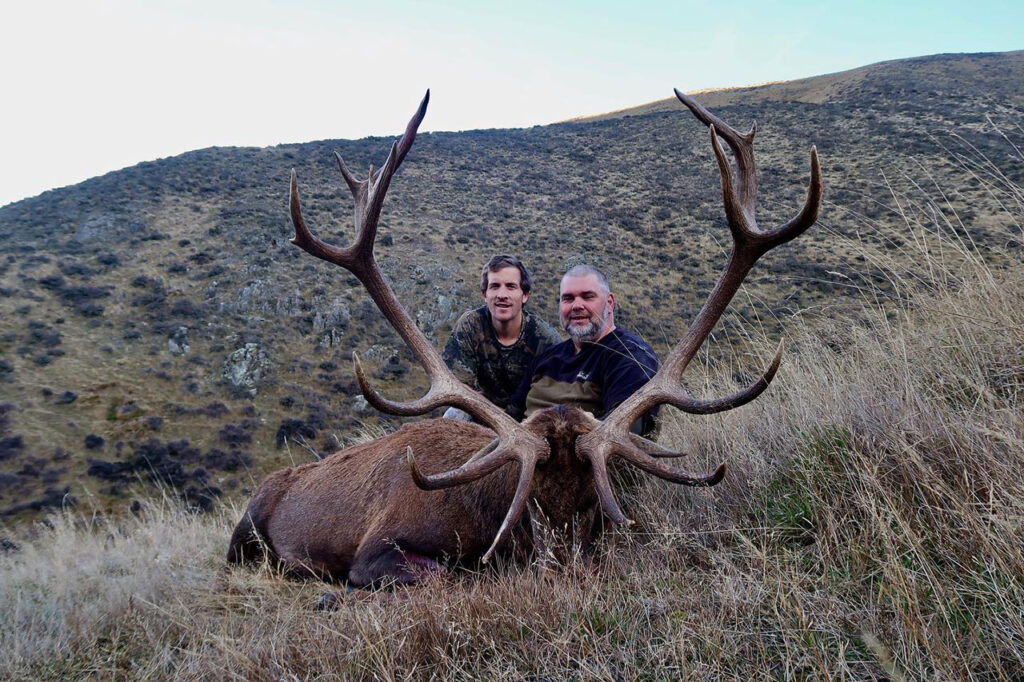 people posing with a large antlers